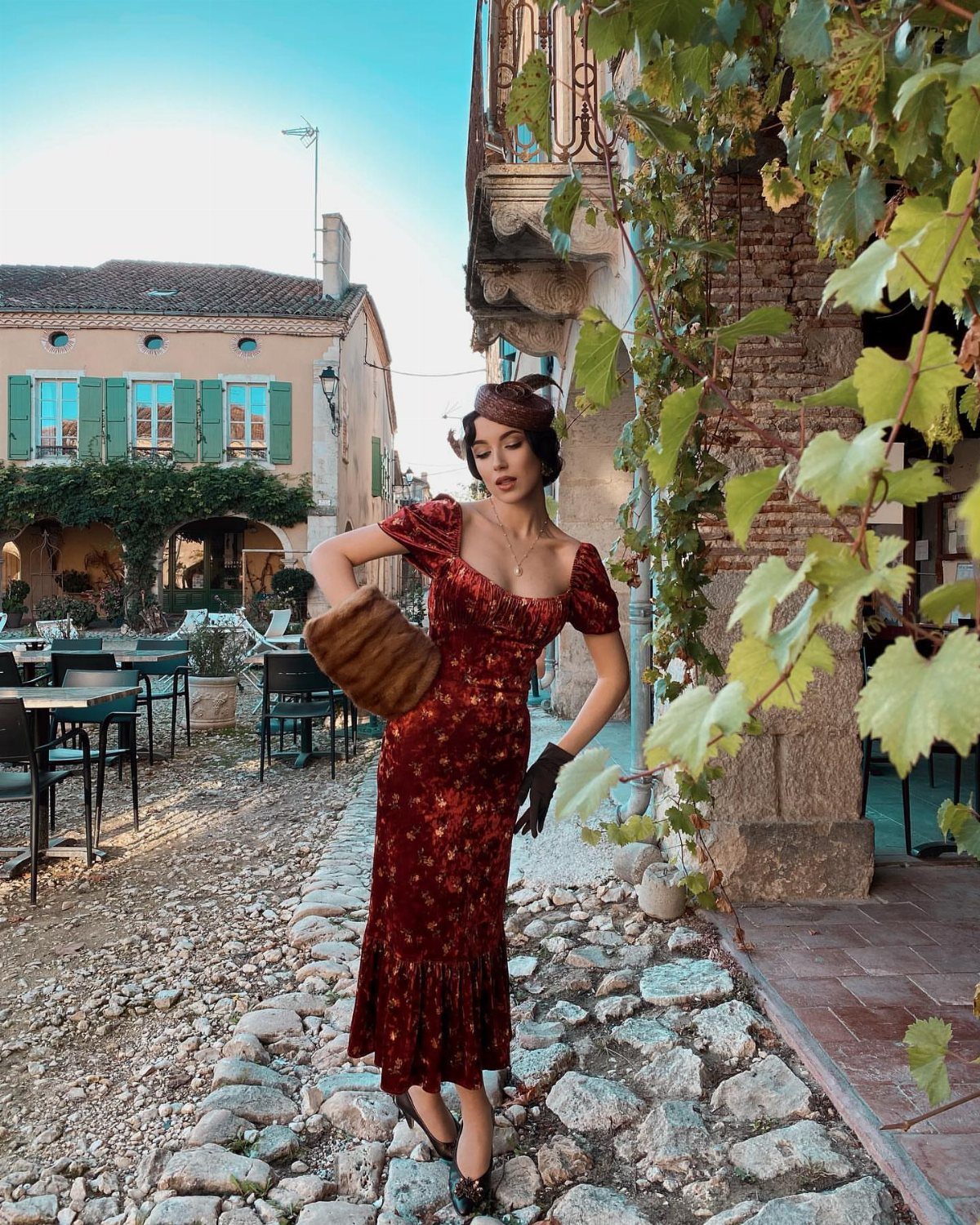 Woman in a red floral vintage midi dress posing on a cobblestone street.