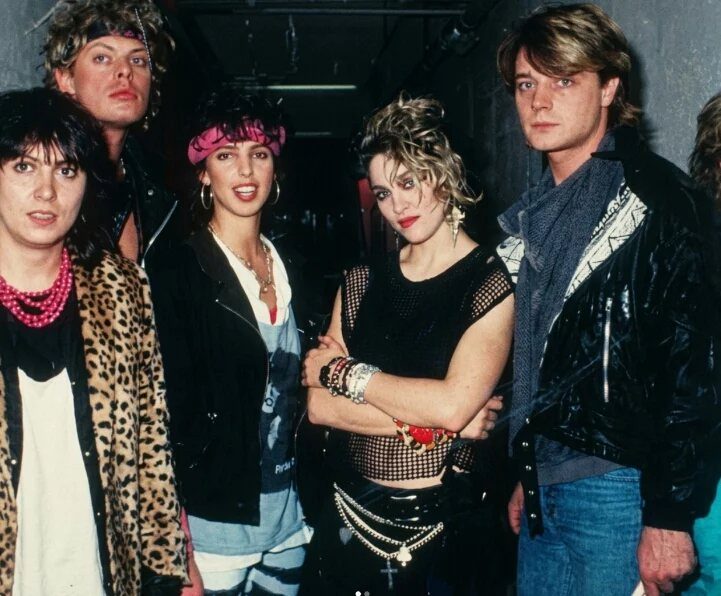 Madonna and her group posing in various 1980s inspired punk and pop fashion outfits.