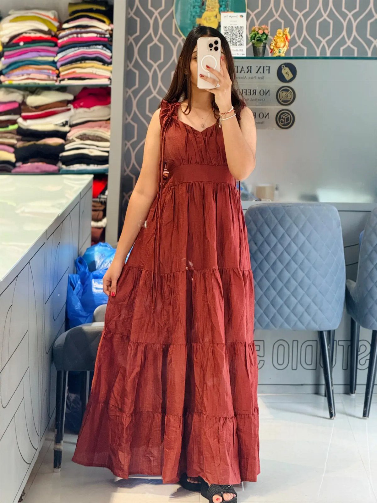 A woman posing in a rust-colored tiered maxi dress while taking a mirror selfie.