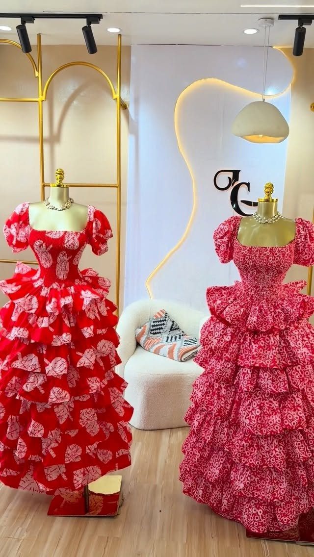 Two vibrant patterned tiered maxi dresses displayed on mannequins in a bright boutique.