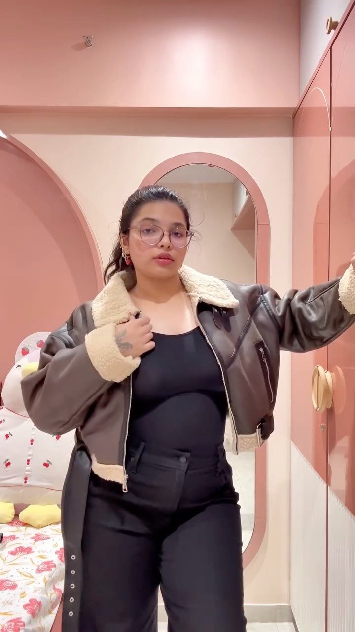 A woman wearing a brown leather aviator jacket with a white shearling collar and black clothing.