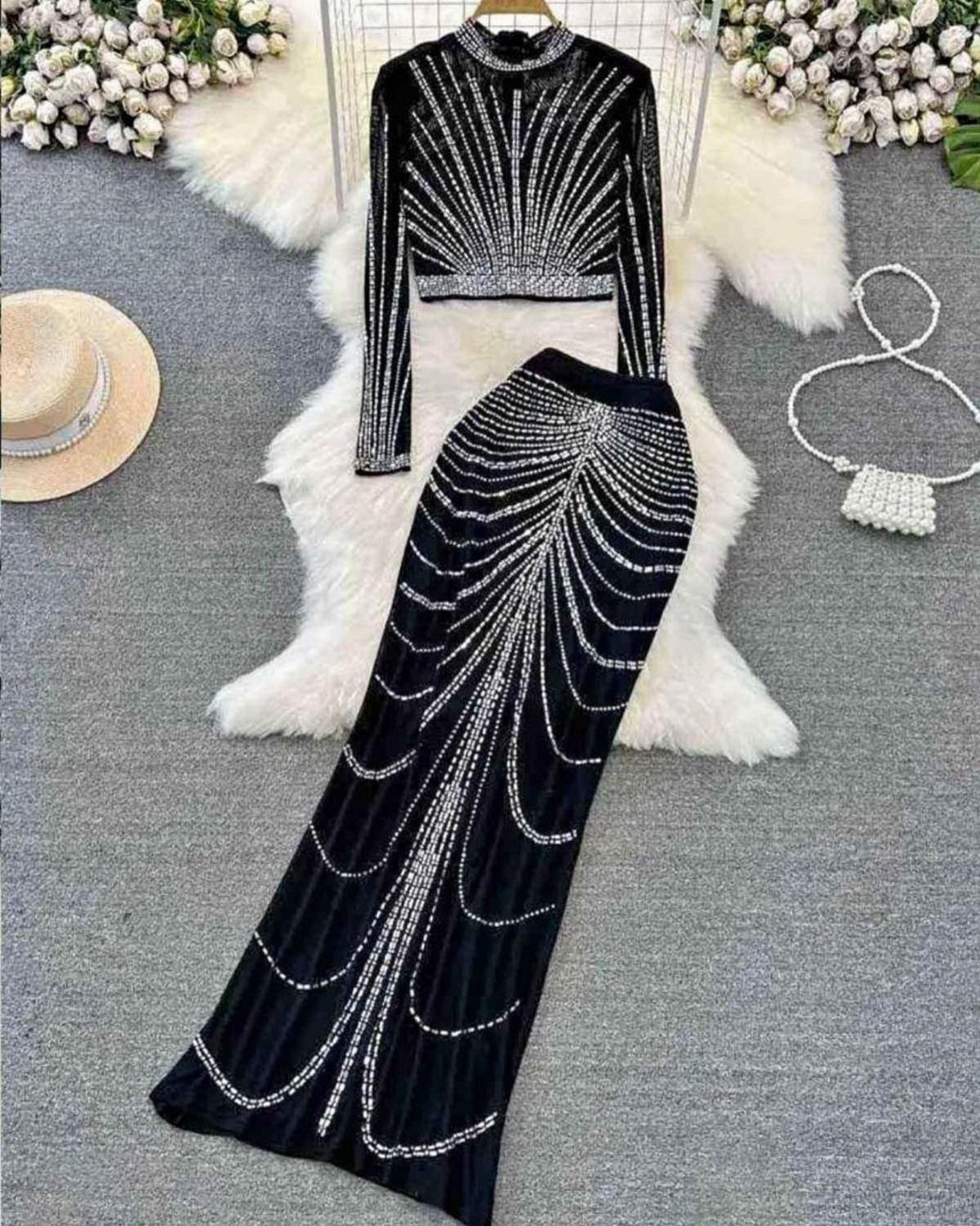 Black velvet cropped top and long skirt with silver embellishments laid on white fur.