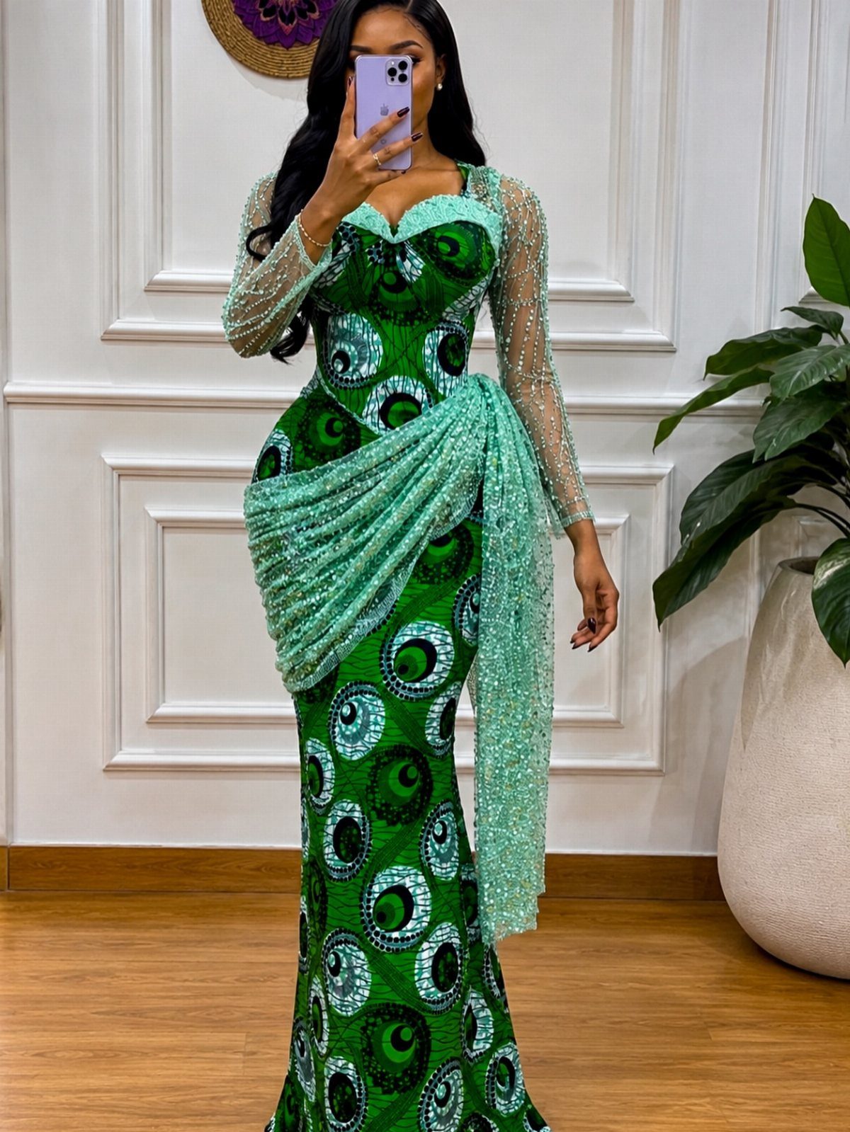 Woman wearing a green patterned Ankara dress with sequined sleeves and draped fabric detail.