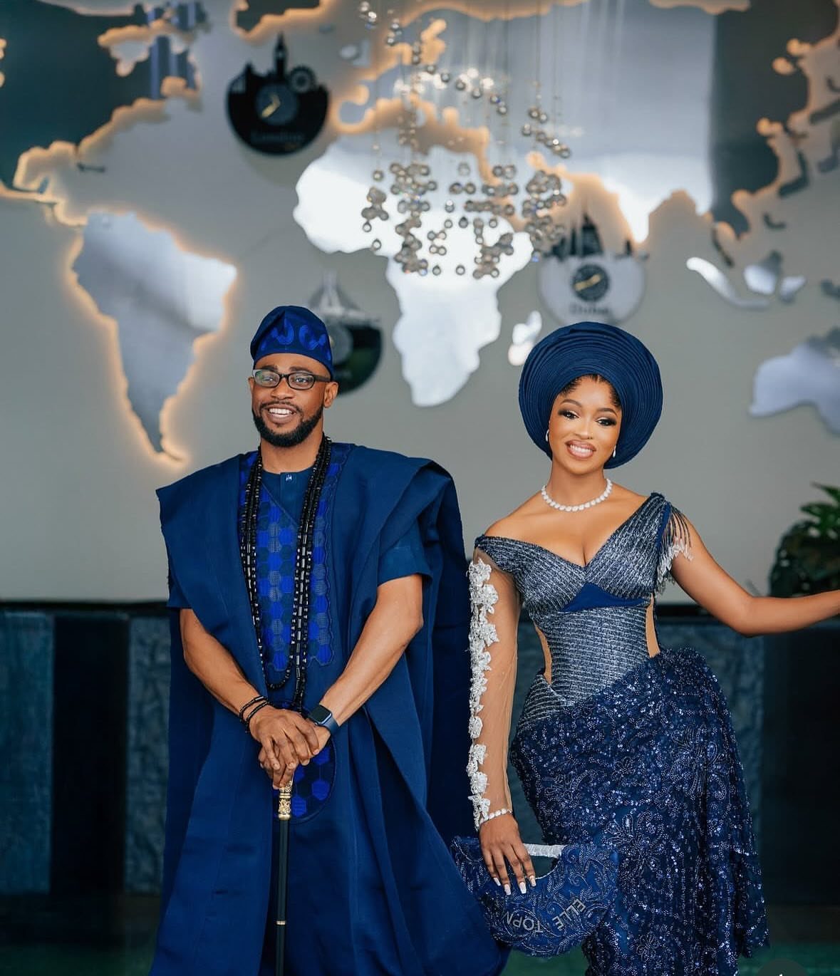 A man and woman posing in matching navy blue Nigerian traditional wedding attire.