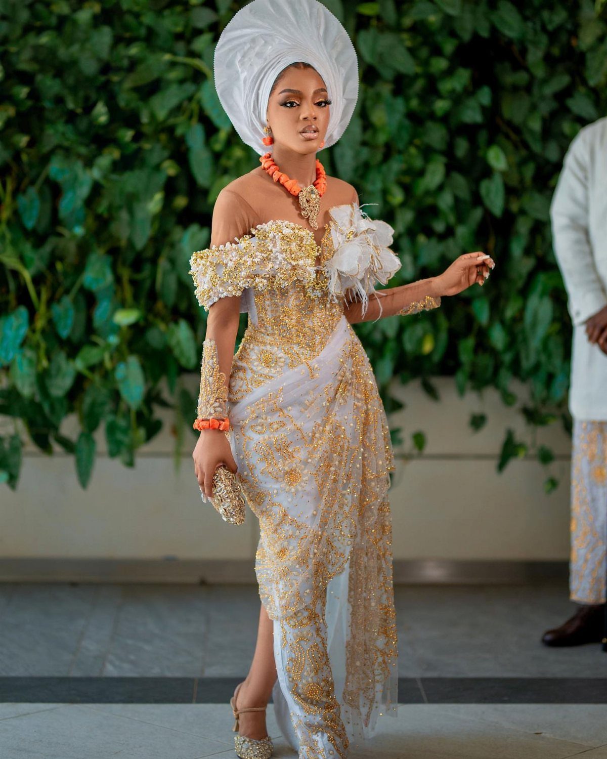 A woman wearing an ornate white and gold Nigerian wedding dress and a large white gele.