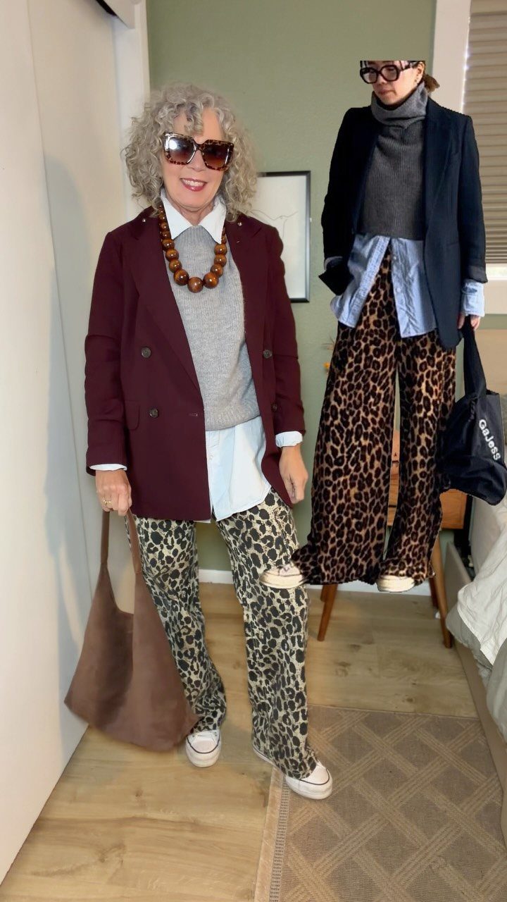 Two women posing in layered outfits featuring blazers, knit sweaters, and leopard print trousers.
