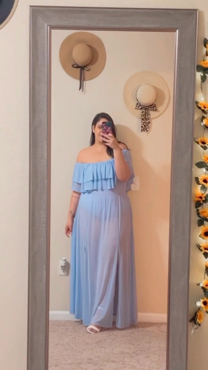 A woman posing in a light blue off-the-shoulder ruffled maxi dress in front of a mirror.