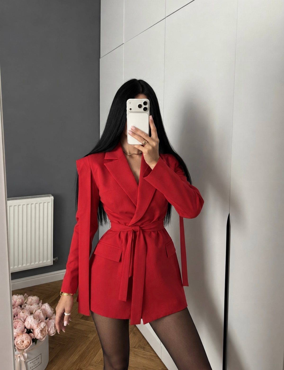 Woman in a red blazer dress posing for a mirror selfie in a room.