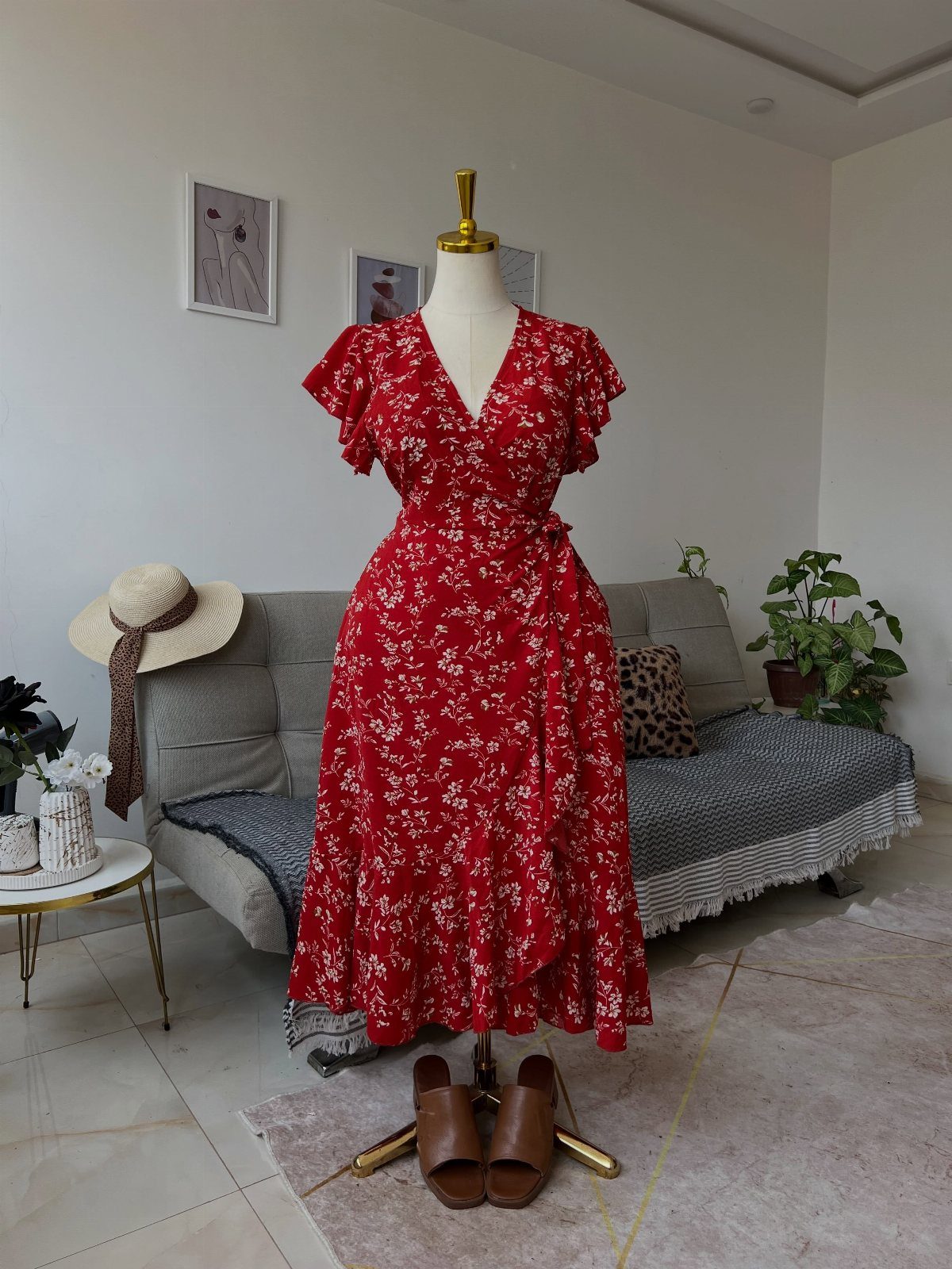 A red floral wrap midi dress displayed on a mannequin in a living room setting.