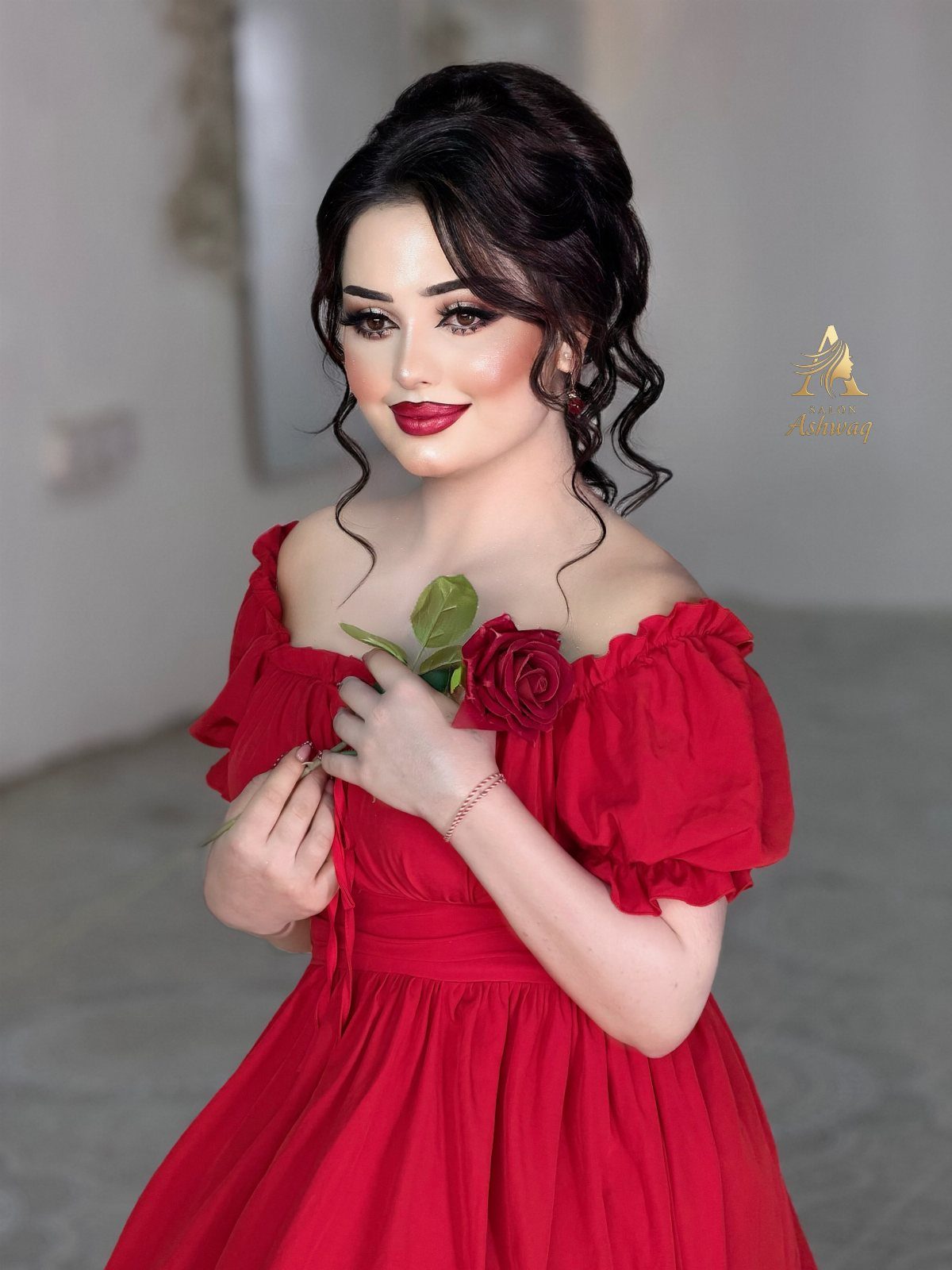 A woman in a red off-the-shoulder dress holding a red rose near her chest.