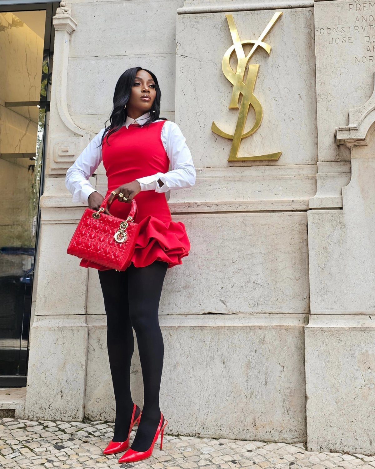 Woman in a red dress over a white shirt, black tights, and red heels.
