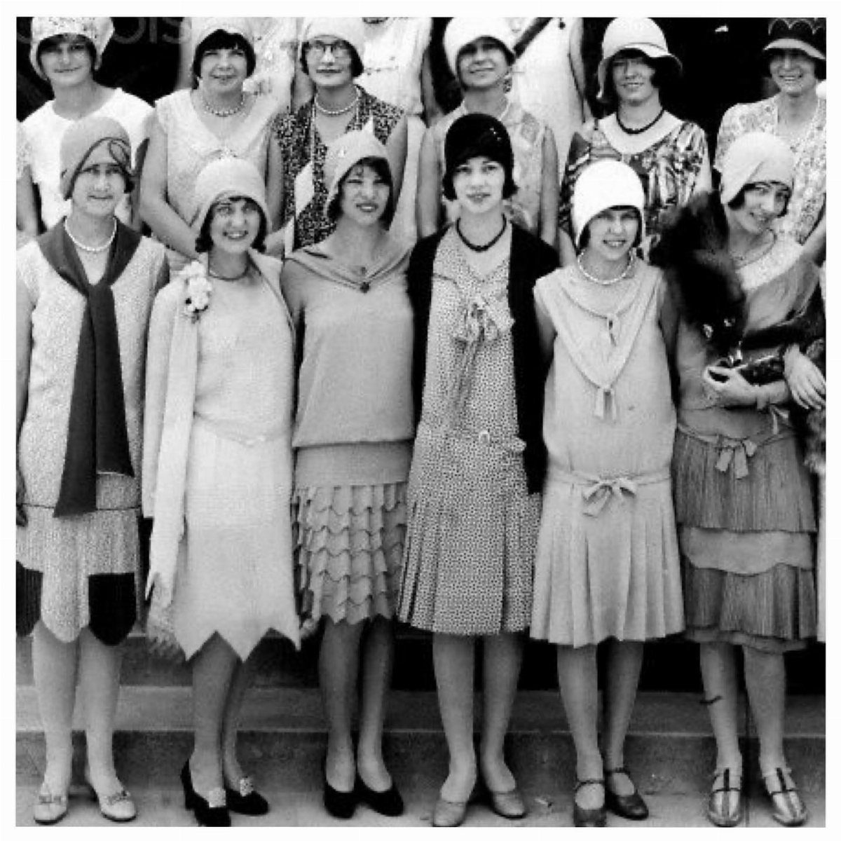 Group of women in 1920s fashion wearing various styles of cloche hats and vintage dresses.