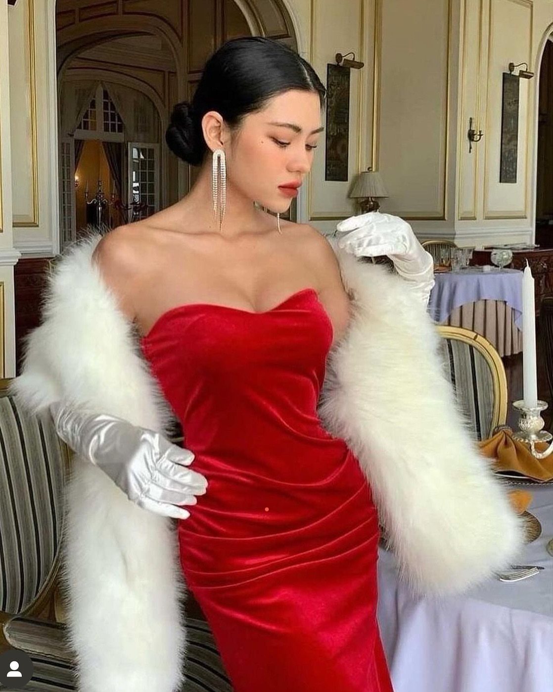 Woman in a red velvet dress wearing a white faux fur stole and satin gloves.