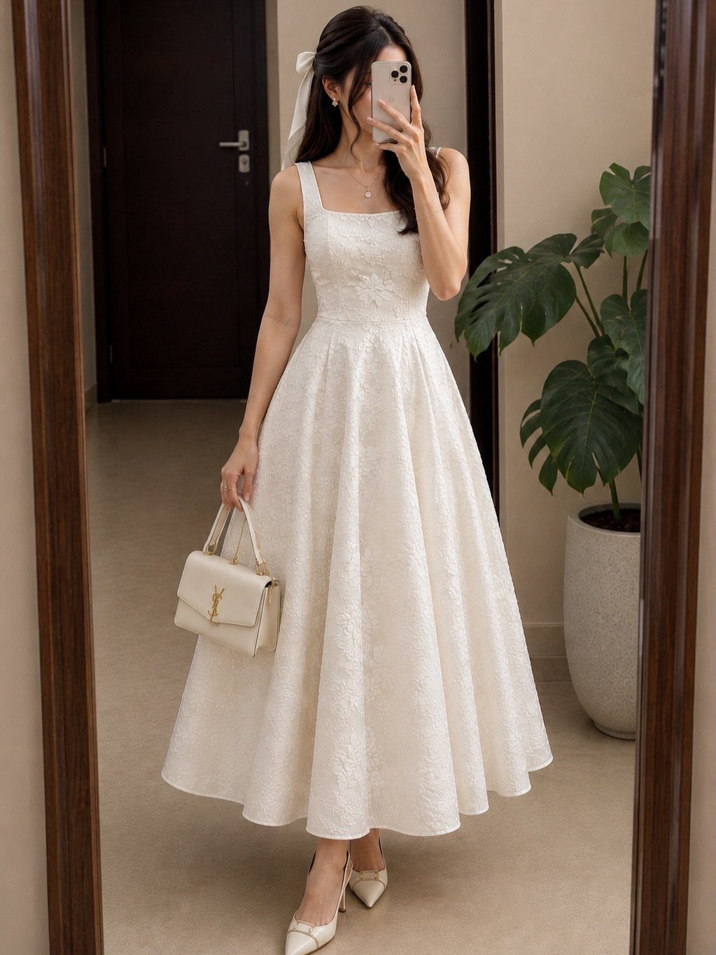 Woman in a white textured sleeveless midi dress holding a cream handbag in a mirror selfie.