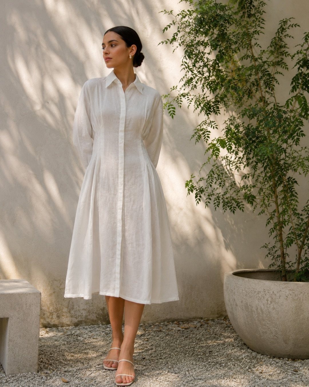 Woman wearing a white long-sleeved linen midi dress with a flared skirt standing outdoors.