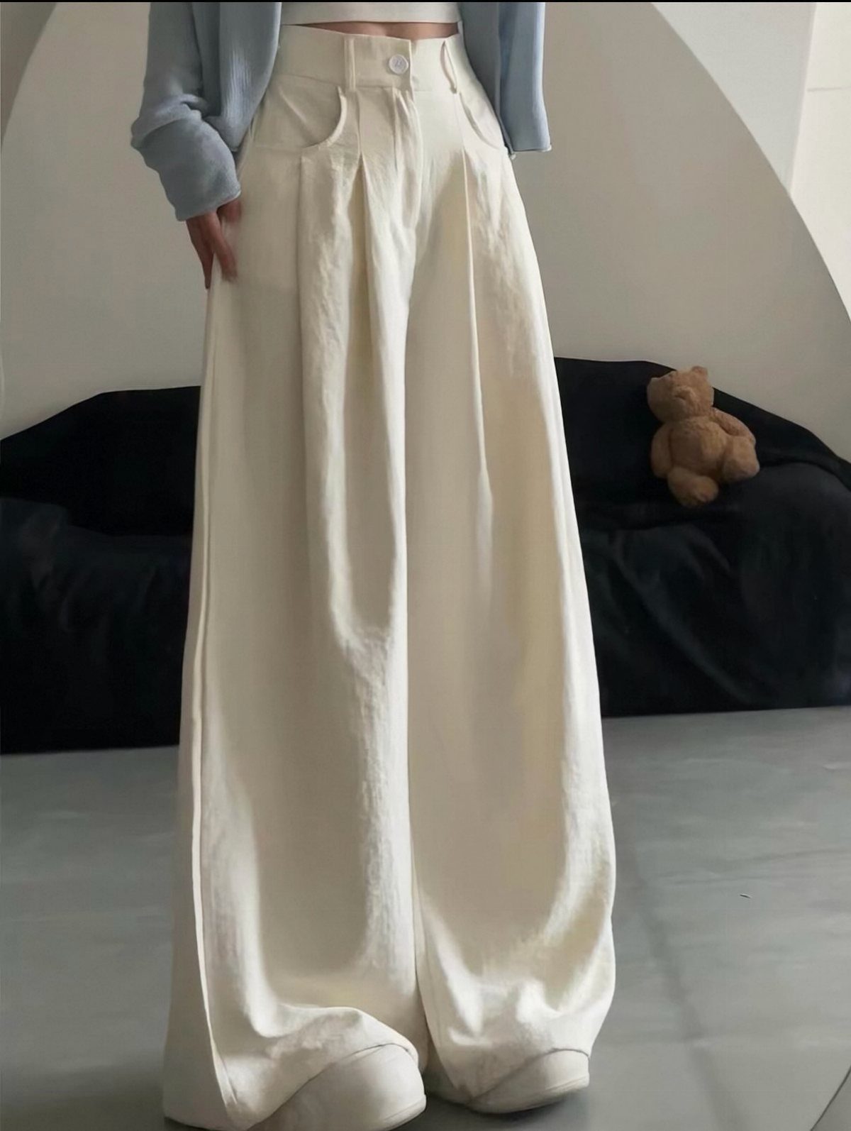 Cream wide-leg trousers worn by a person paired with a light blue cardigan.