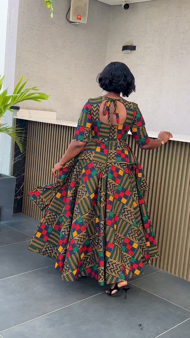Woman wearing a long, colorful patterned African print dress with a flared skirt and keyhole back.