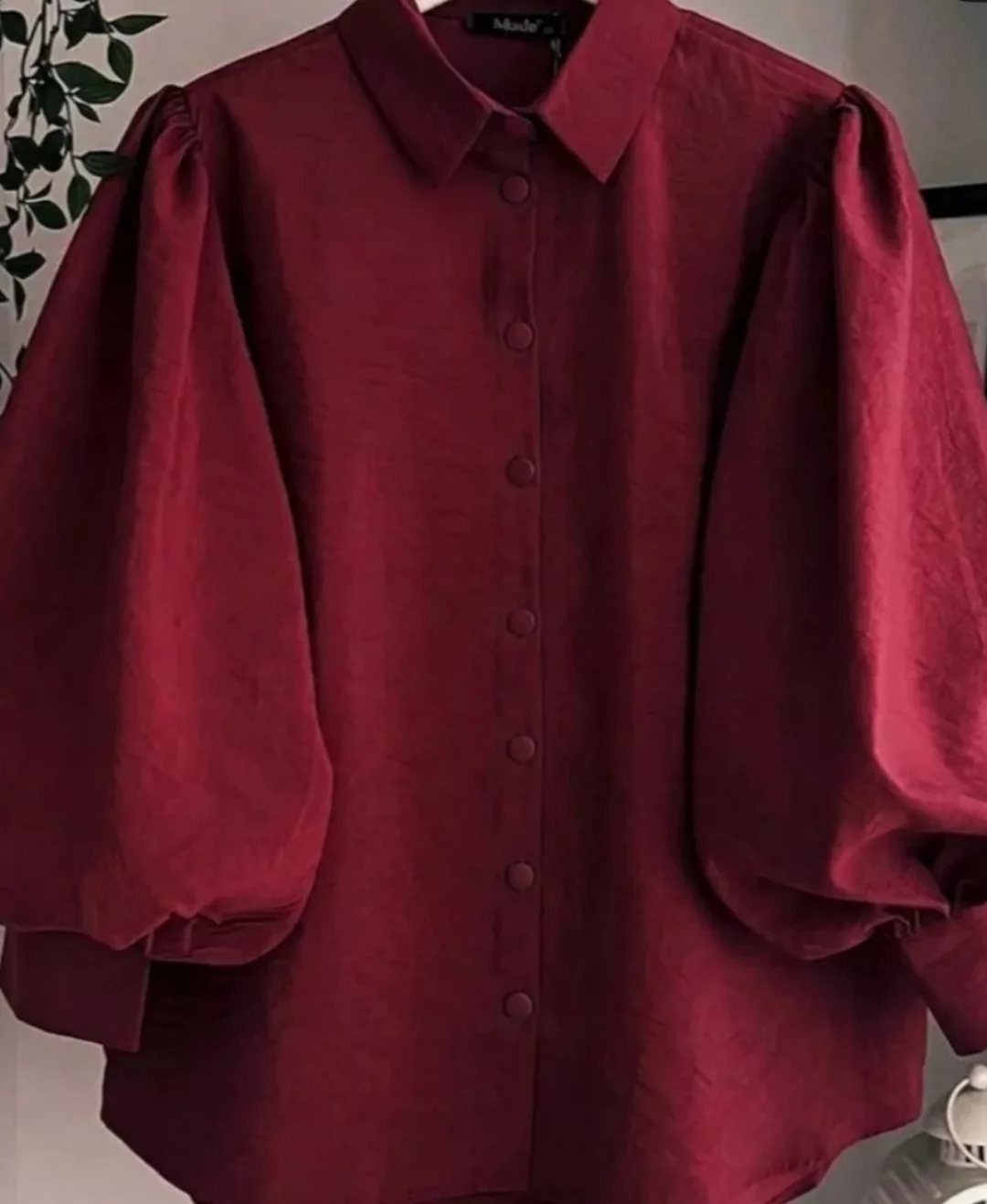 A dark red button-down blouse featuring large, voluminous puff sleeves and a pointed collar.