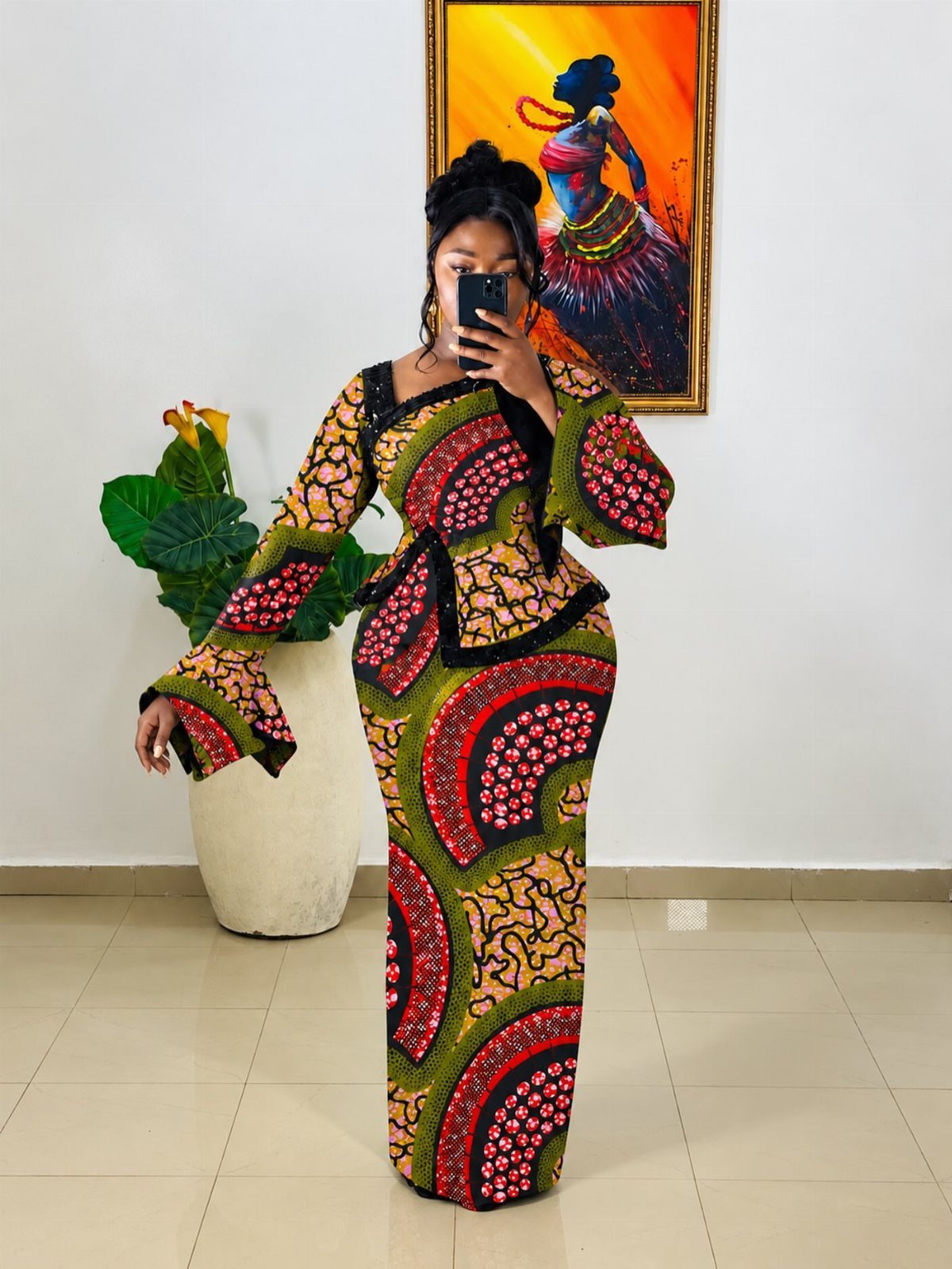 A woman wearing a colorful patterned dress with large, dramatic bell sleeves posing for a selfie.