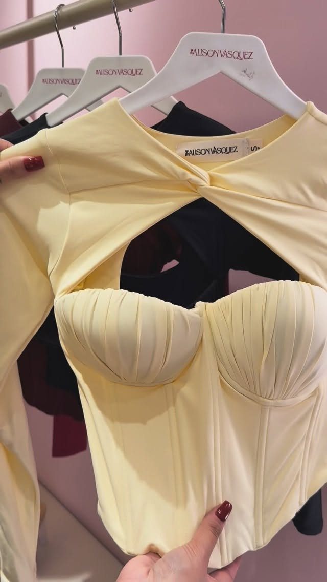 A pale yellow long-sleeved top featuring a structured corset bodice with vertical seams and gathered cups.