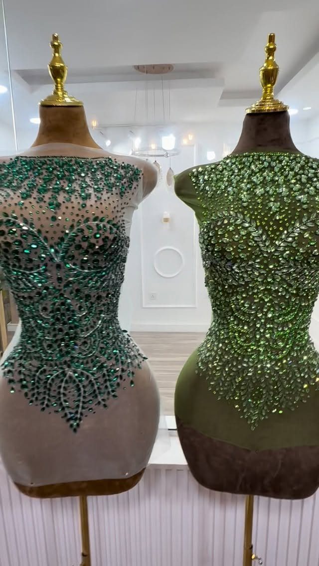 Two mannequins showcasing different styles of heavily embellished green beaded bodices for dresses.