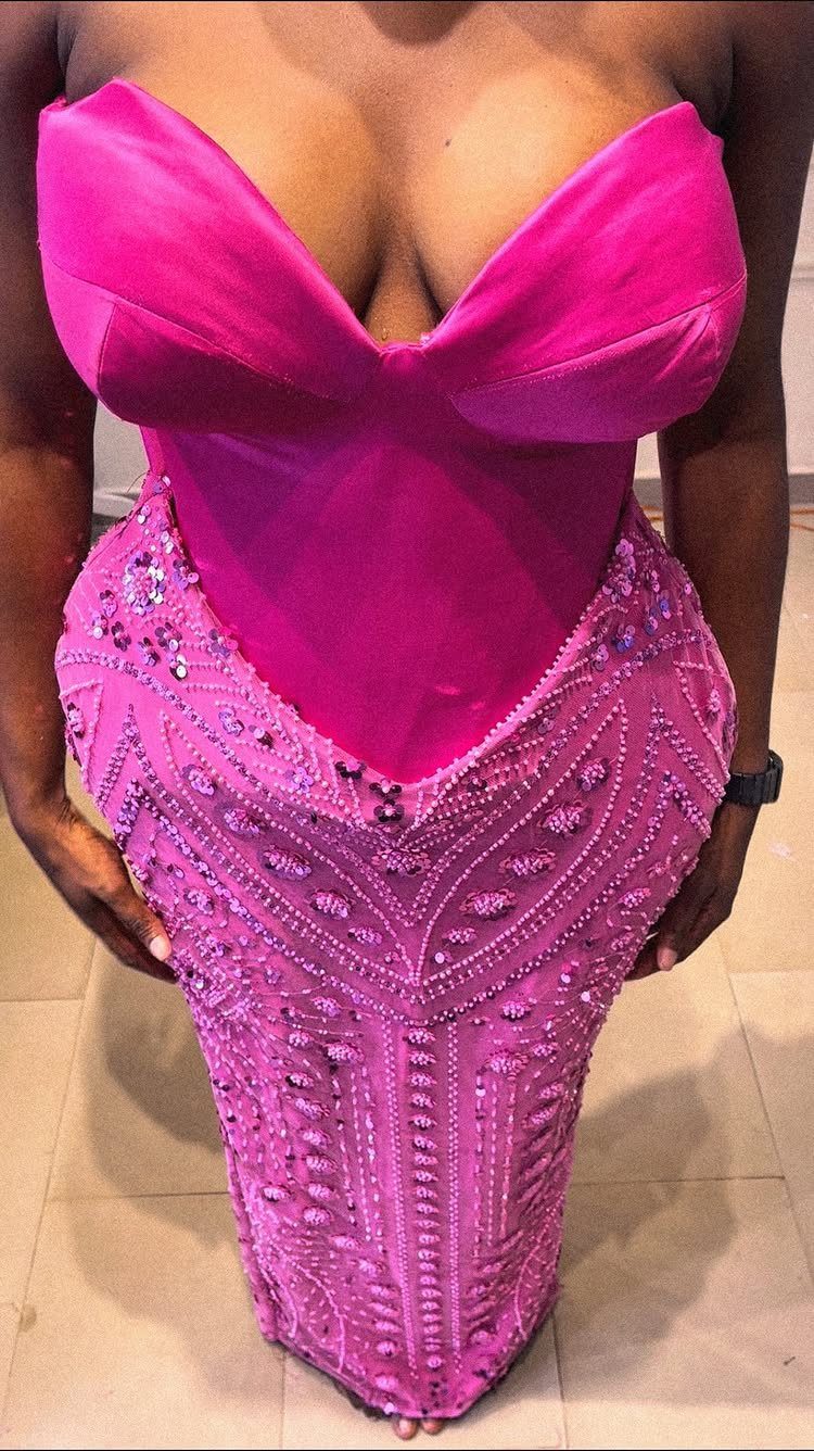 A person wearing a bright pink strapless dress with a sweetheart neckline and beaded skirt.