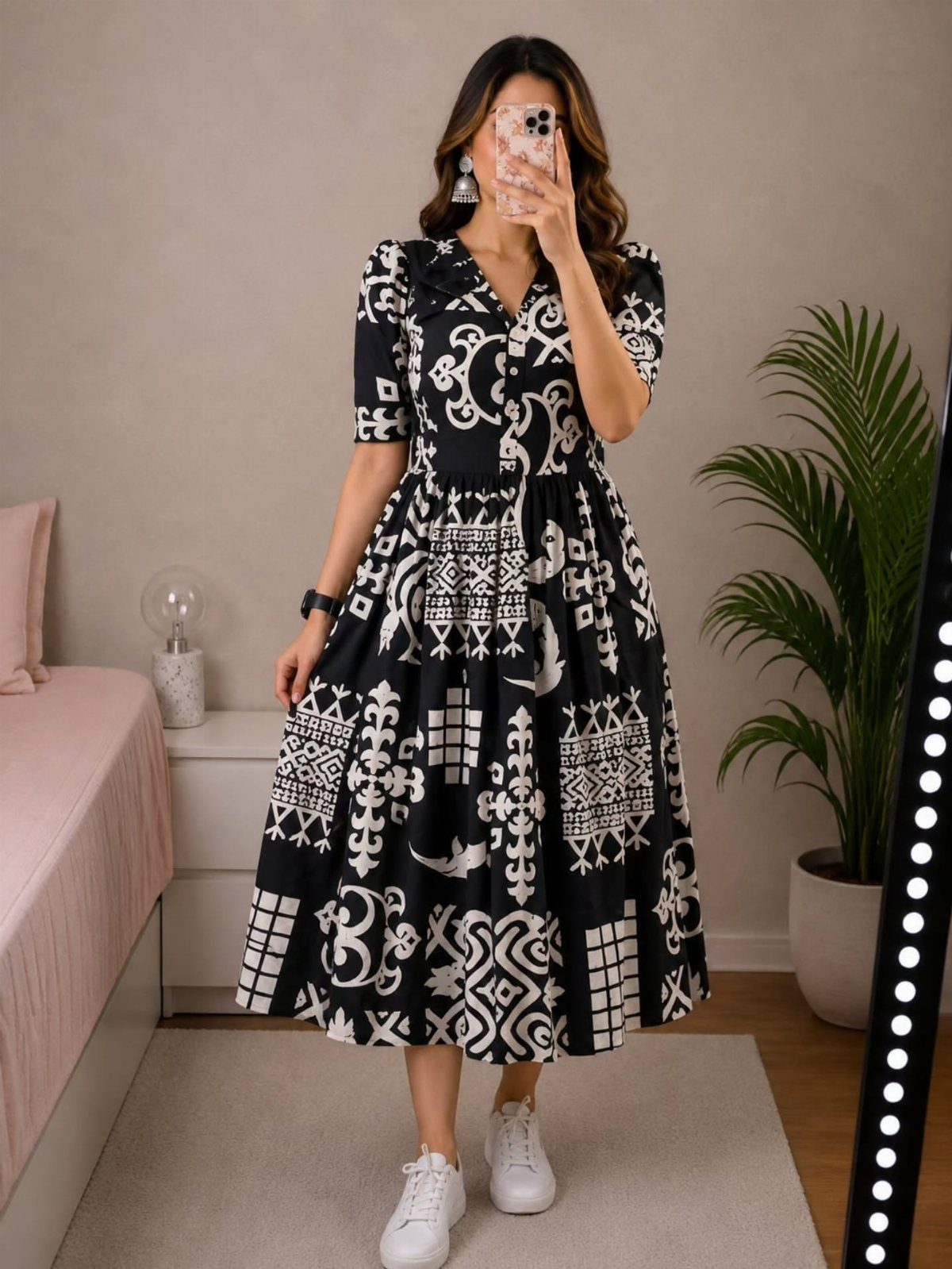 Woman in a black and white patterned midi dress standing in a room.