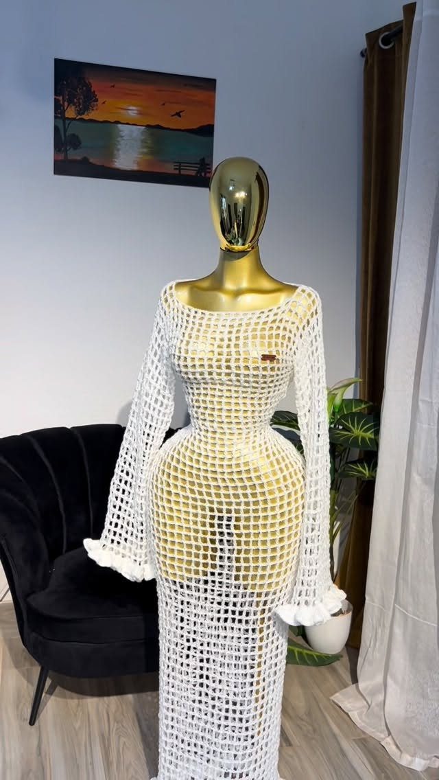 White crochet maxi dress with long flared sleeves displayed on a gold mannequin.