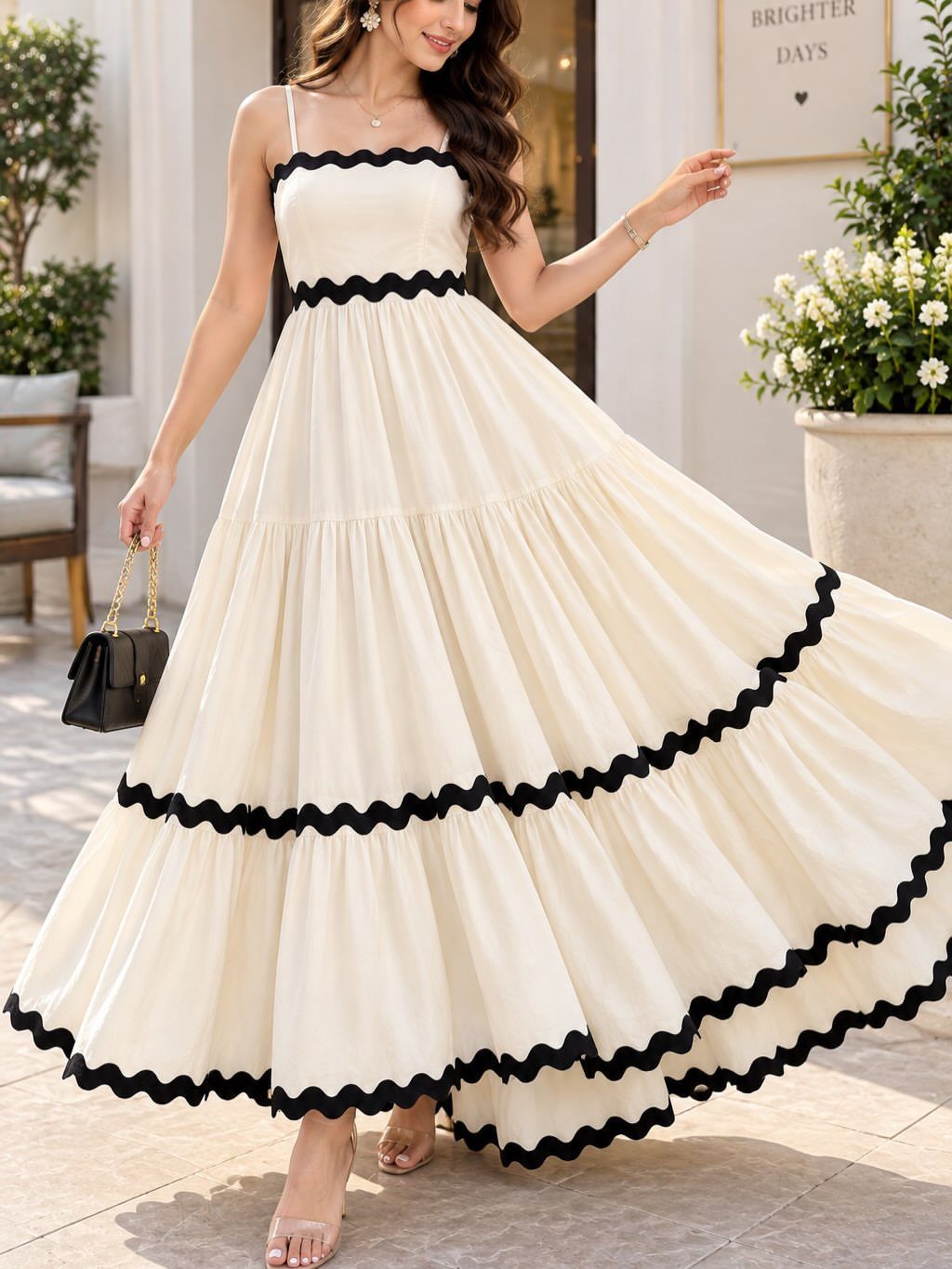Woman wearing a cream sleeveless maxi dress with black scalloped trim edges.