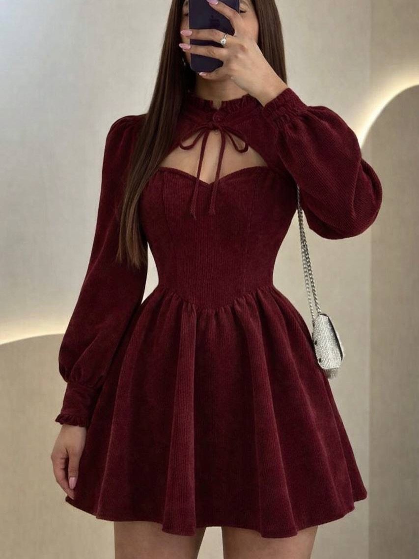 Woman wearing a burgundy corduroy long-sleeved mini dress with a cutout neckline.