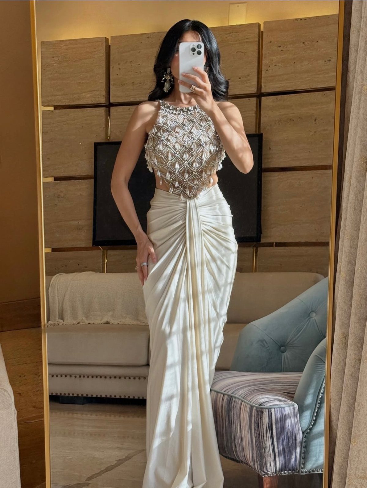 Woman wearing a white formal gown with an embellished top and a draped skirt.