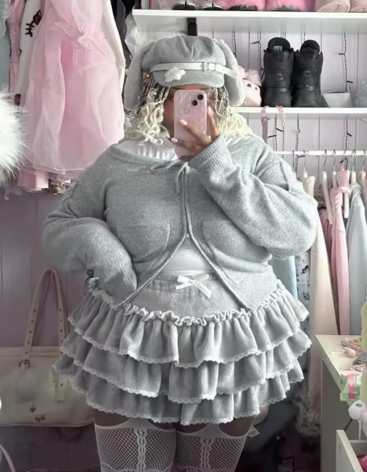 A person wearing a grey tiered ruffle skirt with white lace trim and a matching cardigan.