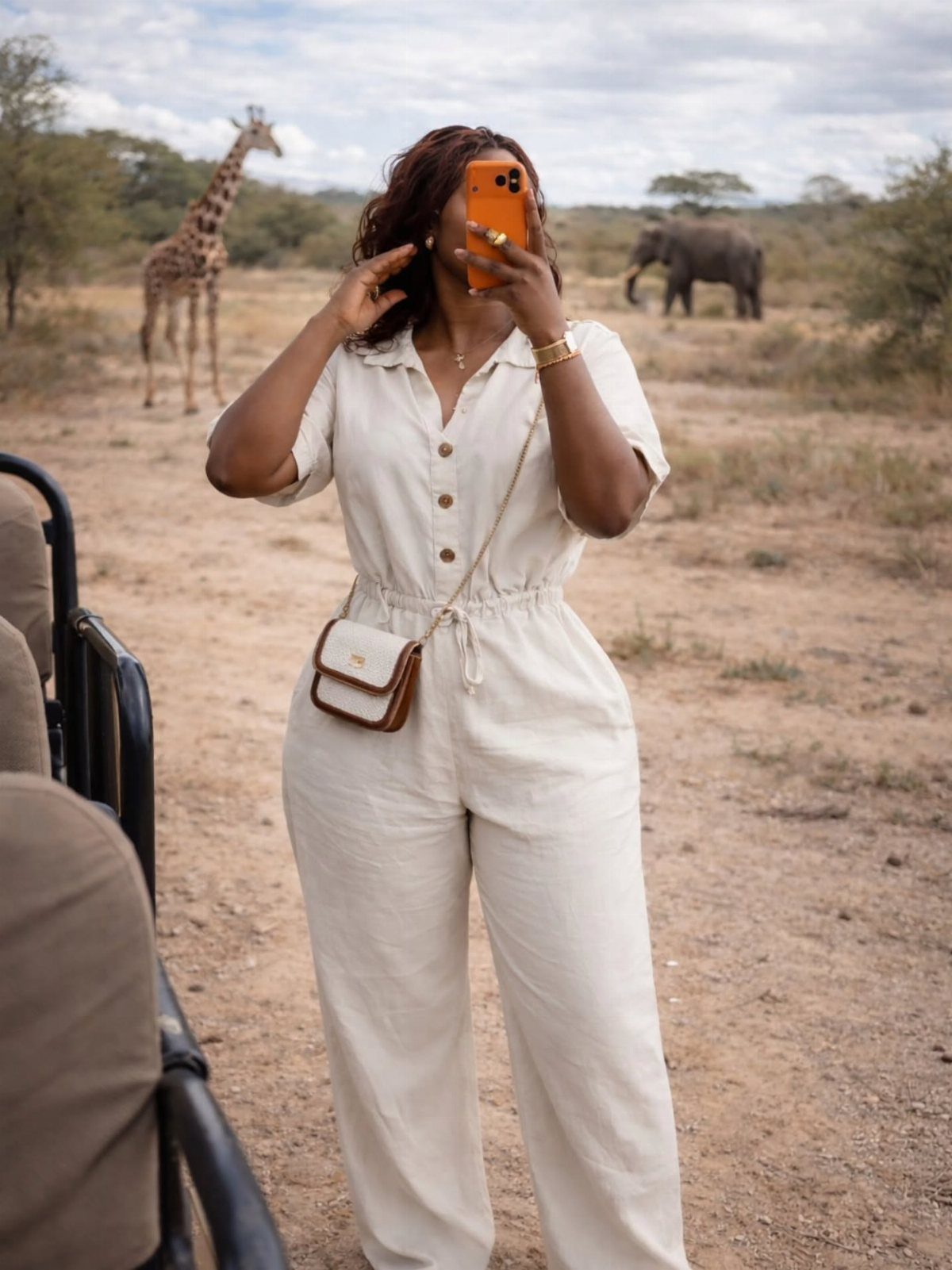 Woman in a cream linen jumpsuit posing for a selfie in a savanna landscape.