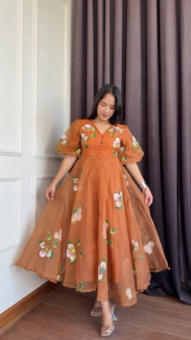 Woman posing in an orange floral puff sleeve fit and flare midi dress.