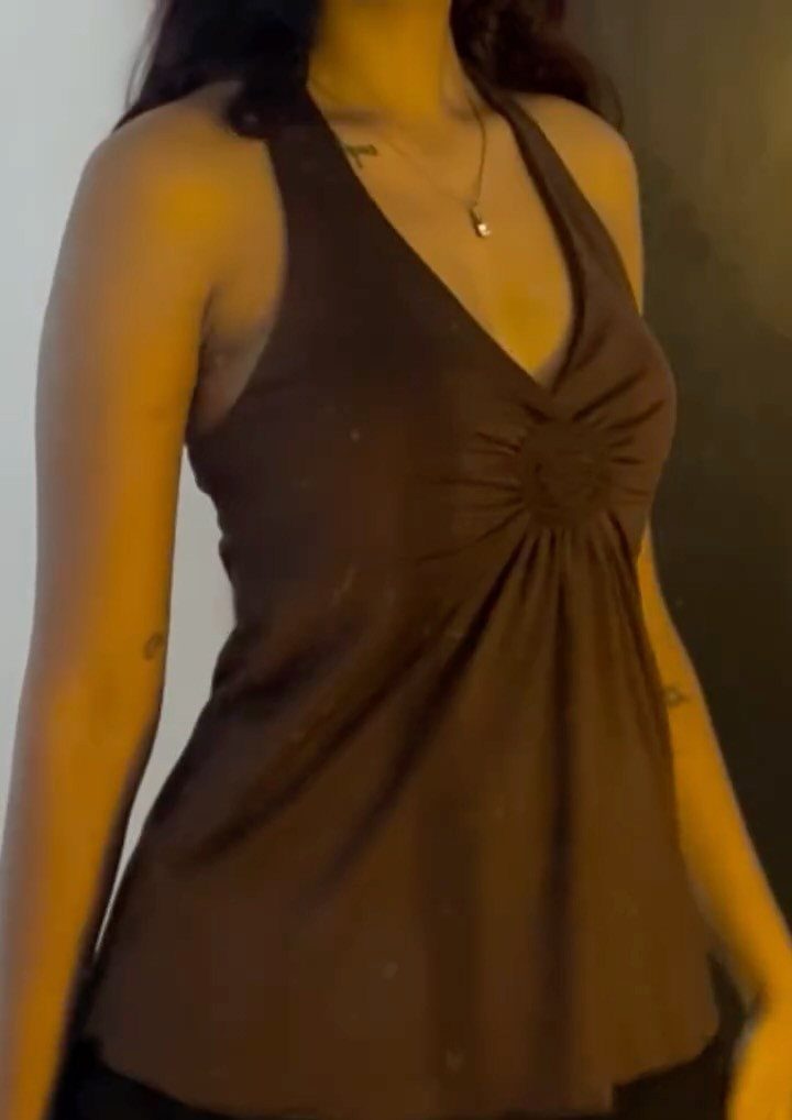 A person wearing a dark brown halter top with a gathered V-neckline and silver necklace.