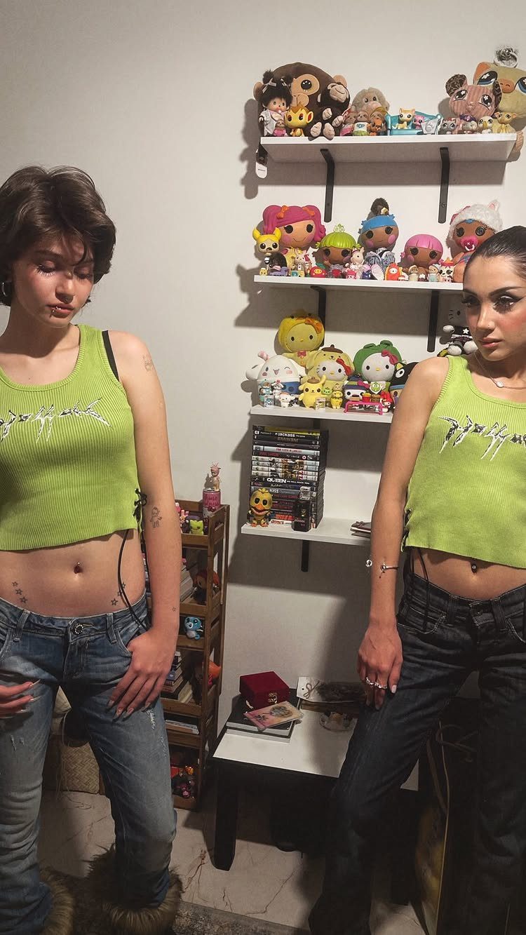 Two young women posing in lime green cropped tank tops and low-rise denim jeans.