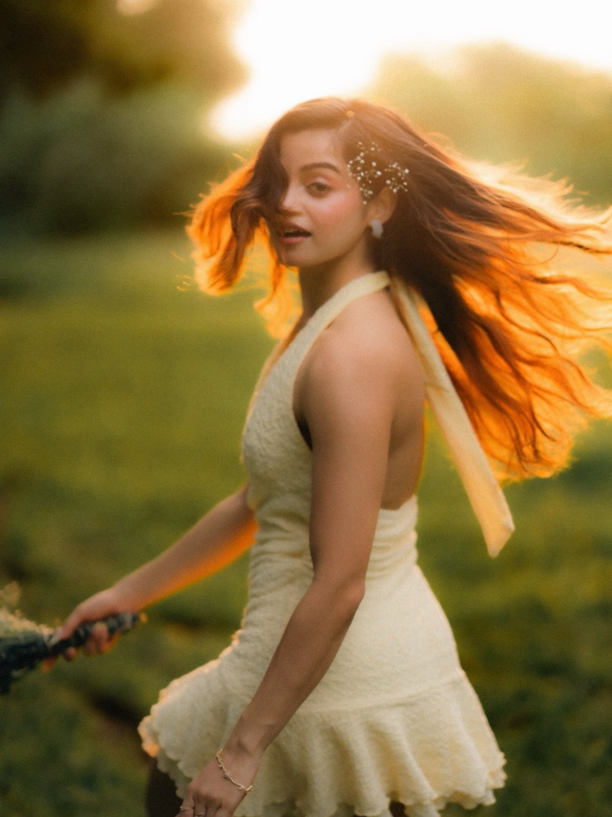 A woman in a pale yellow textured mini dress standing in a sunlit field.